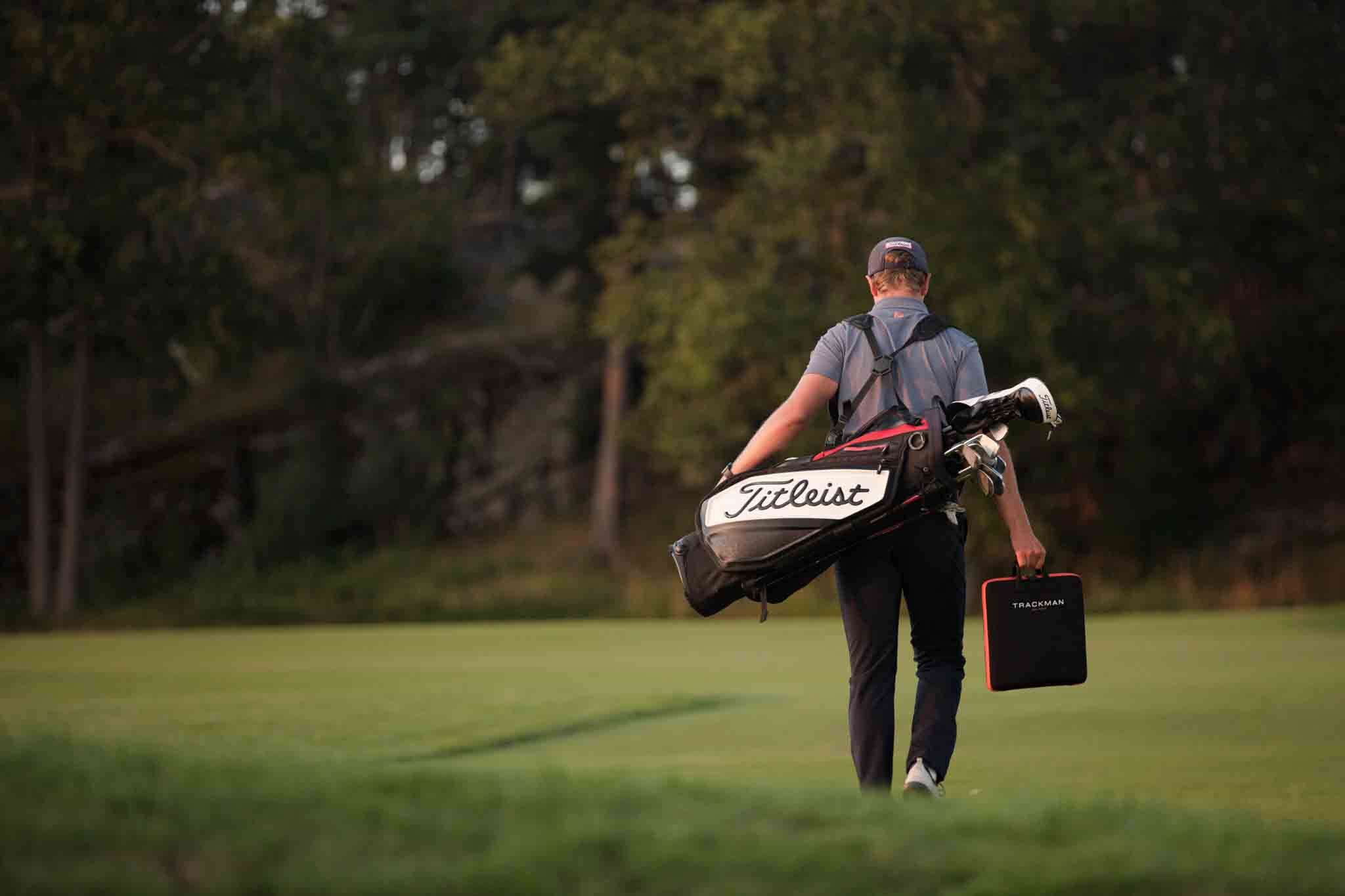 A golfer walking off the course with a golf bag full of clubs from a professional Tee Box Gilbert club fitting.