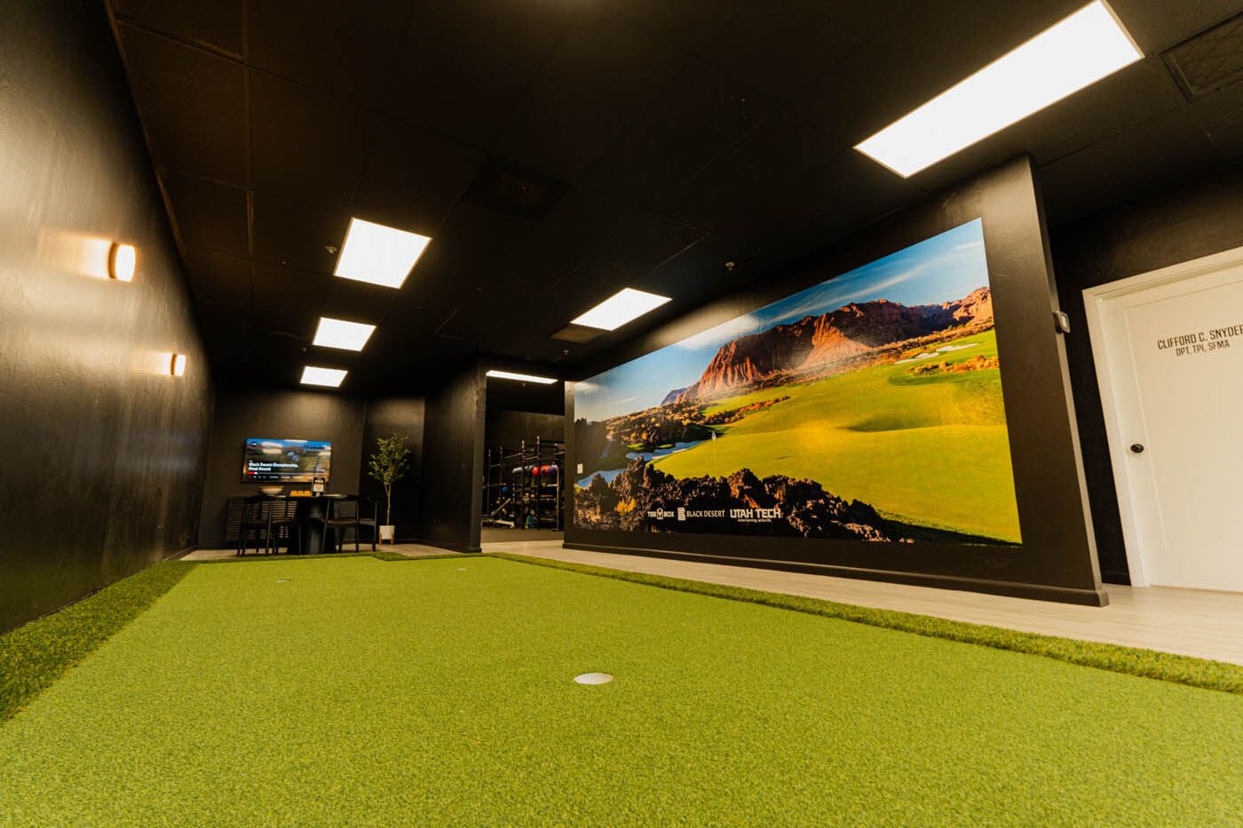 Tee Box St. George indoor putting area with mural and seats.