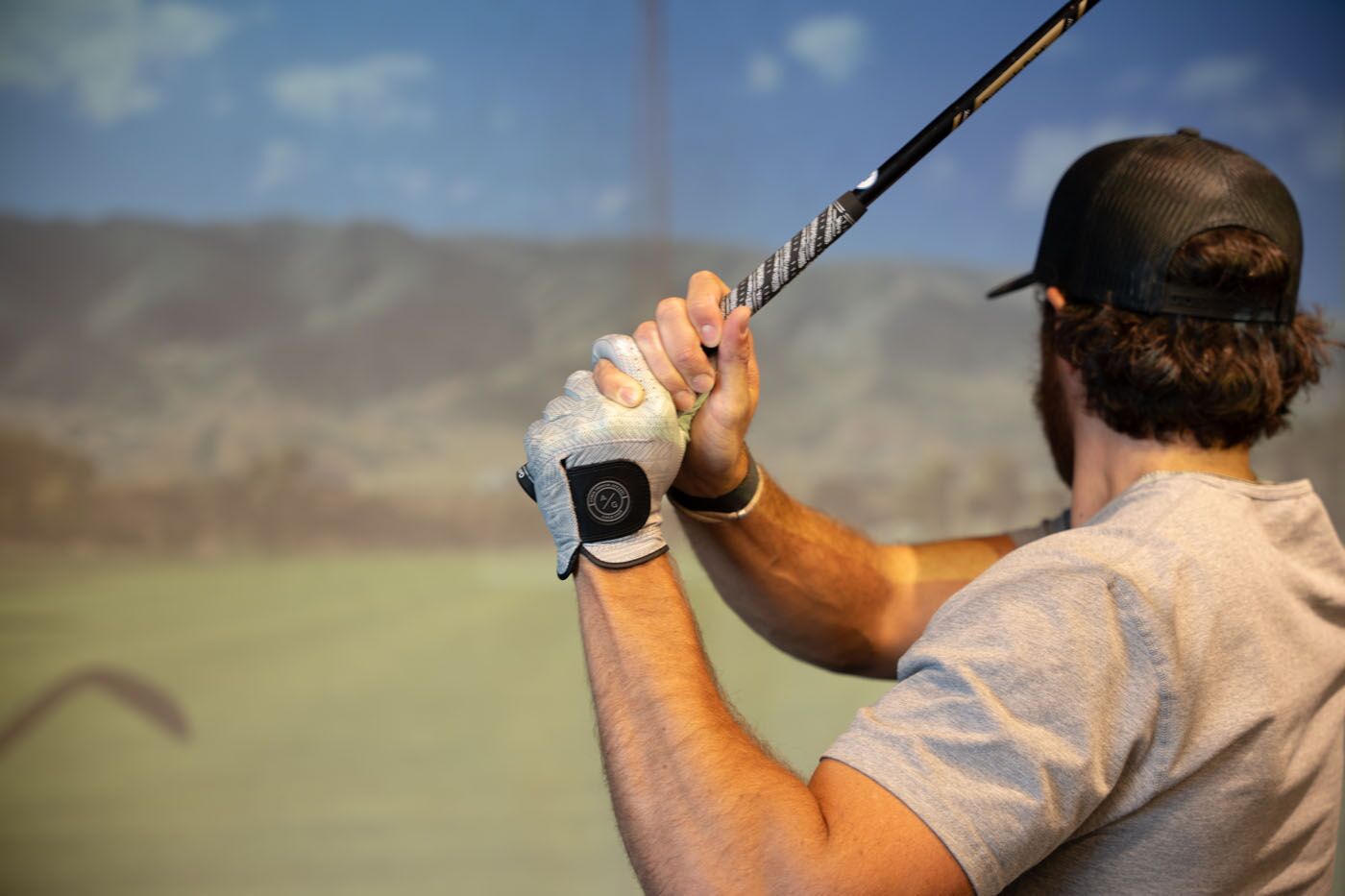 A golfer mid-swing at Tee Box Fort Lauderdale.