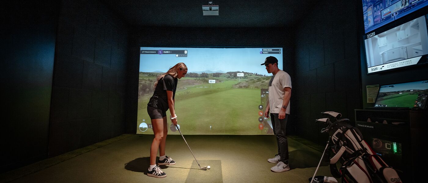 A woman meeting with a Tee Box coach for Pleasant Grove ladies golf lessons.