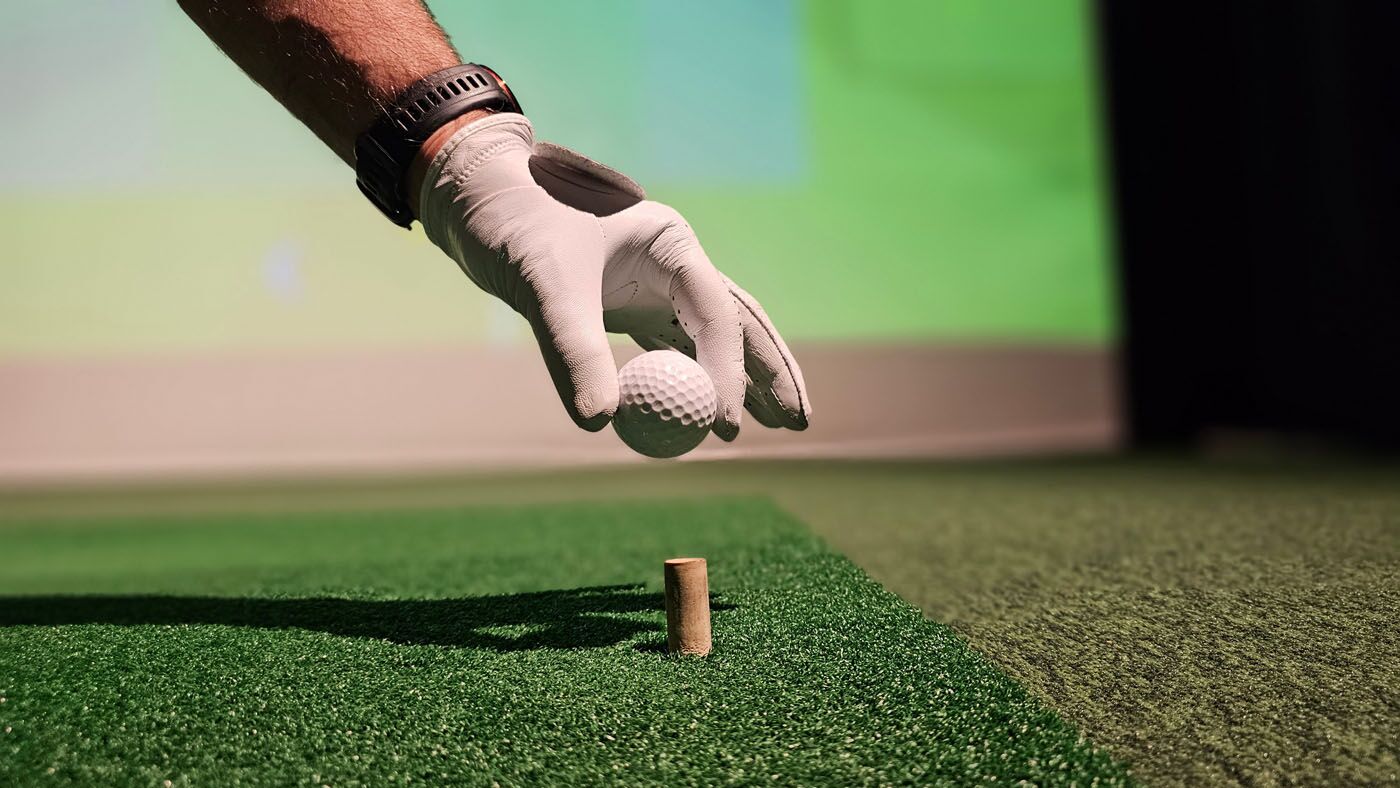 An image of a person teeing up a golf ball at Tee Box Central Houston.